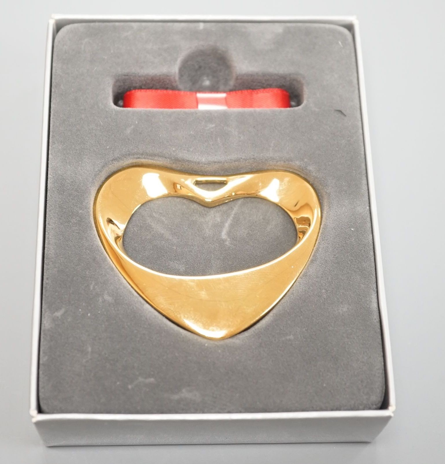 A modern Georg Jensen gold plated open work heart shaped pendant, no. 152A, width 55mm, with red and blue sashes and box.